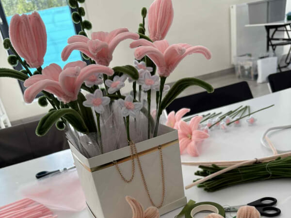 Bukiet zrobiony z drucików kreatywnych. Po bokach znajdują się części do dalszego tworzenia bukietu.