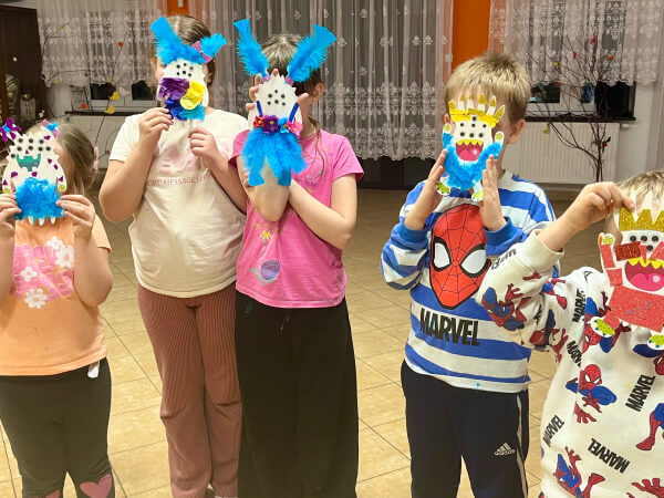 Dzieci trzymają przed twarzami potworki z papieru.