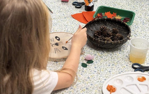 Dzieci robią zwierzątka na plastrze drewna.