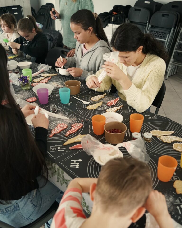 Uczestnicy dekorują ciastka aromatyzowanym lukrem.